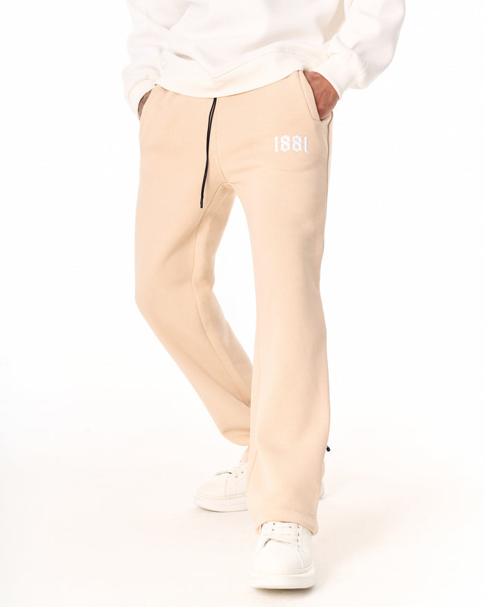 Martin Valen 1881 oversized beige men's jogger, rear view showing ankle drawcord and white sneakers