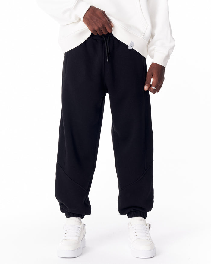 Martin Valen black corded joggers worn front view, showing gathered ankles, curved stitch panels and white sneakers