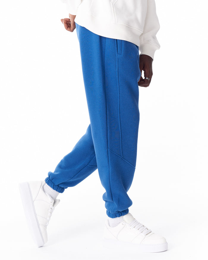 Martin Valen bright blue corded joggers side view with visible stitch detail and elastic cuffs, worn with a white hoodie