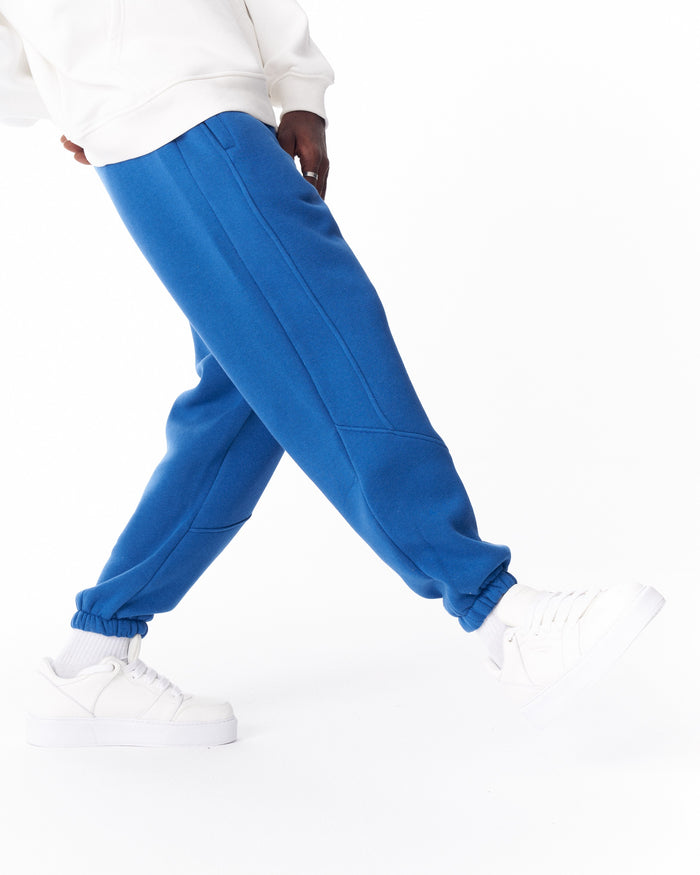 Martin Valen bright blue joggers in motion, close-up on leg seam and pocket edge, paired with white sneakers