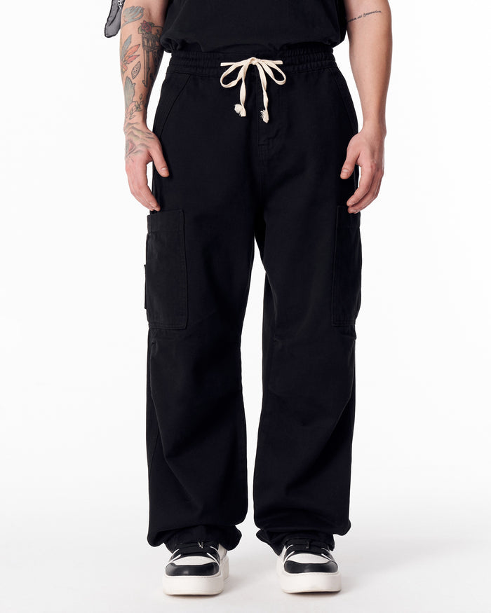 Martin Valen men's oversize black cargo jogger pants, front waist view with white drawstring tied and side pockets